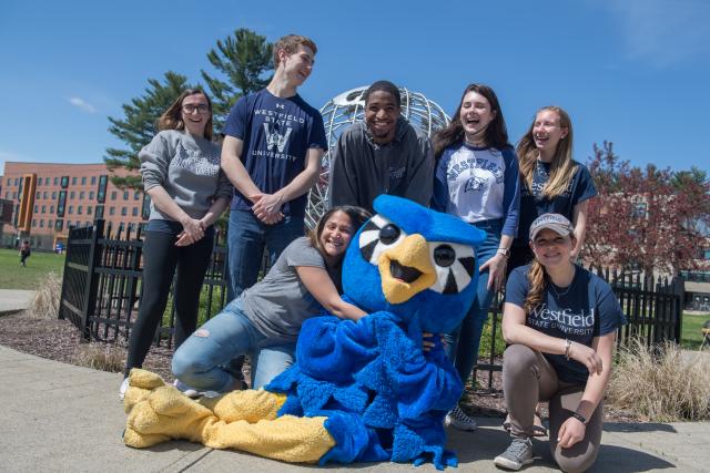 nestor surrounded by students in front of the globe on the campus green