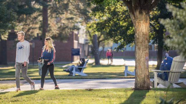 students walking across the campus green in the late afternoon