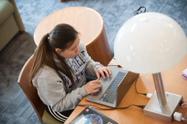 Female student working her laptop in the Ely Library