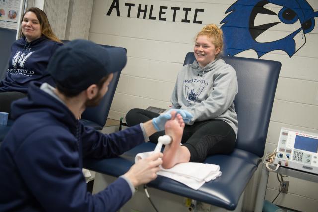 A Westfield Student Sports Medicine student works with another student.