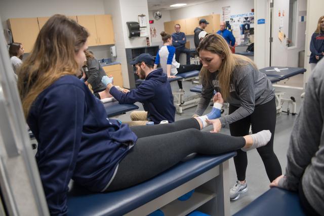 A Westfield State student aids with wrapping an ankle.