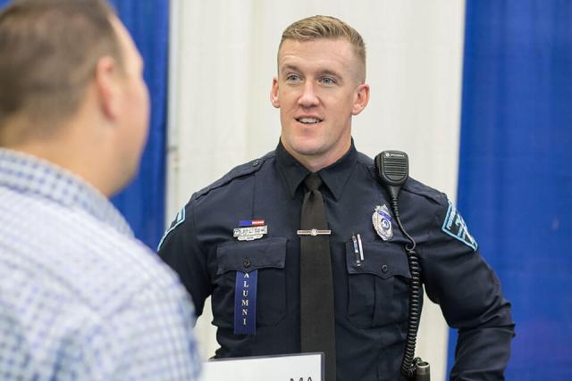  A Westfield State University alumnus in police uniform engages in conversation.