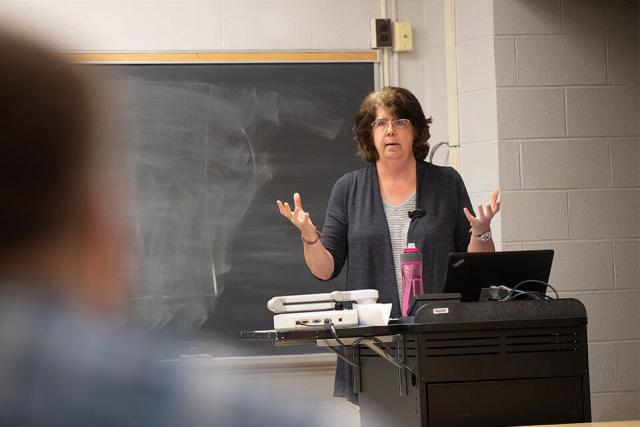 female professor lecturing at front of classroom