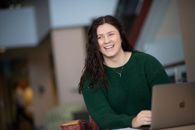 Woman student smiling while typing on laptop