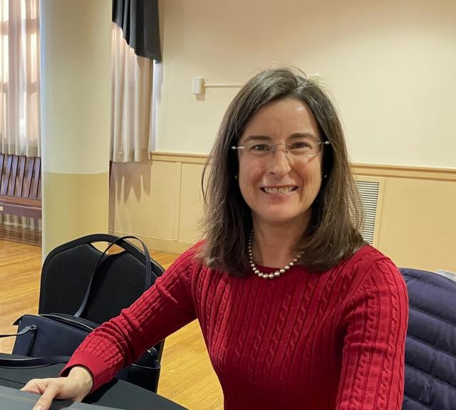 Accounting professor smiling wearing red shirt and glasses.