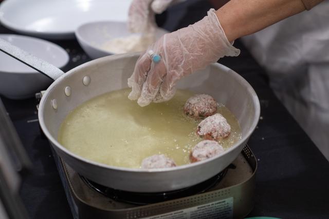 Cooking with Maria class featuring Greek meatballs cooking in a skillet.