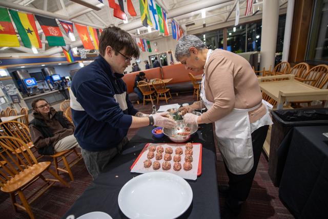 Cooking class with Maria in the Dining Commons. Photo of Maria and participant making Greek meatballs.