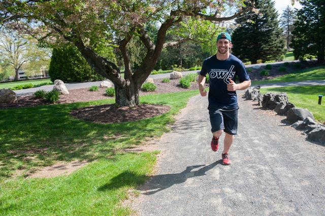 Student running at Stanley Park wearing baseball hat and Owls Hockey shirt.