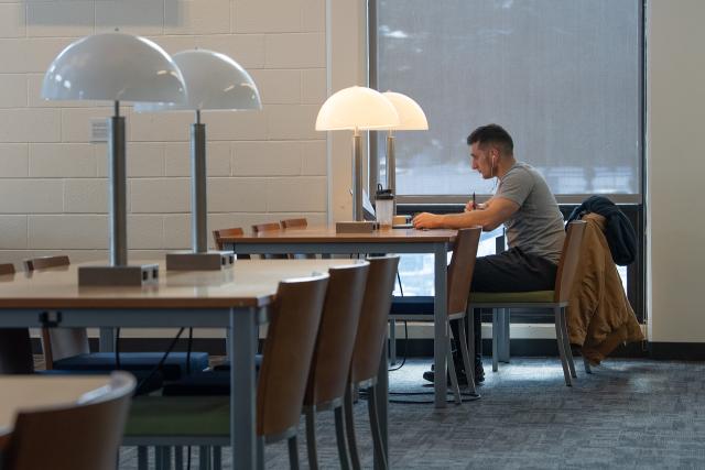 Student studying in Ely wearing grey shirt and black pants with headphones on.