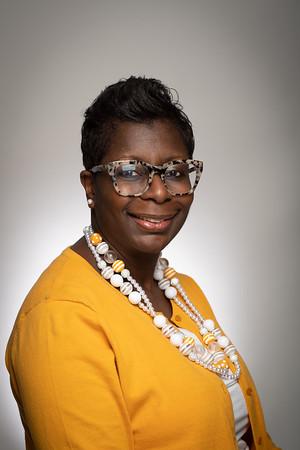 Photo of La-Toya Wilson, Director wearing a yellow shirt and glasses.