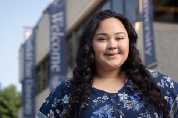 Nisa, LEAD Scholars Program Academic Advisor smiling in front of the Horace Mann Center wearing blue floral shirt.