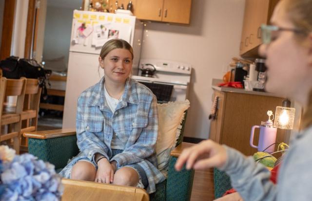 Two students chat while sitting in a shared living room in their on-campus apartment.