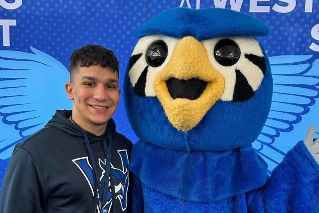 Accepted student smiling alongside Westfield State mascot Nestor.