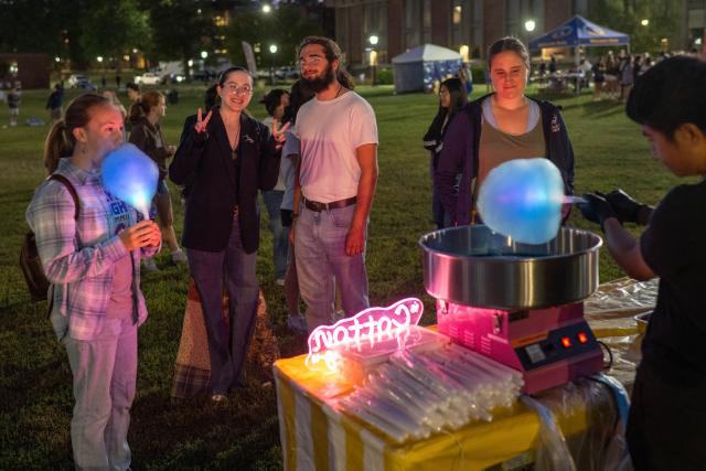 Students gather to get glowing cotton candy on the campus green