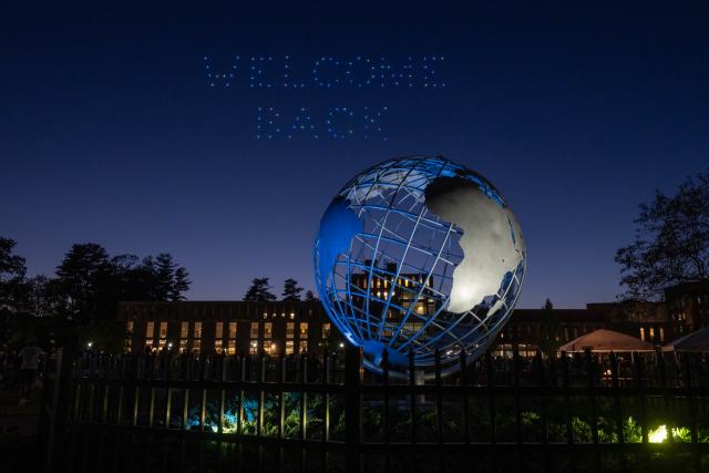 Drone show on campus green with globe and "Welcome Back" above it.