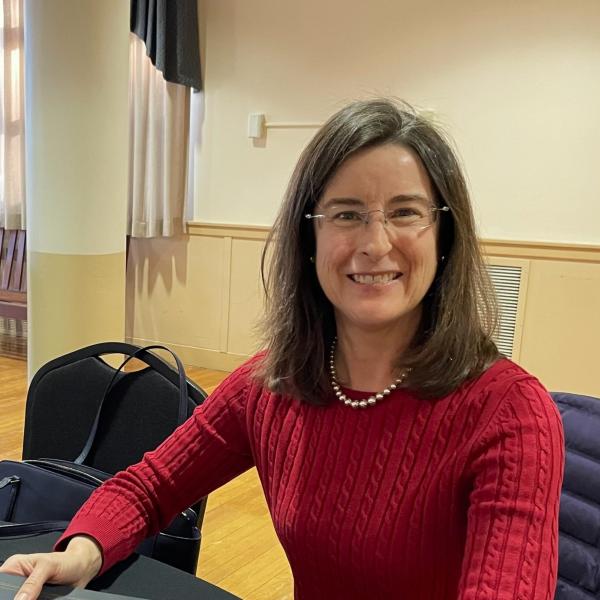 Accounting professor smiling wearing red shirt and glasses.