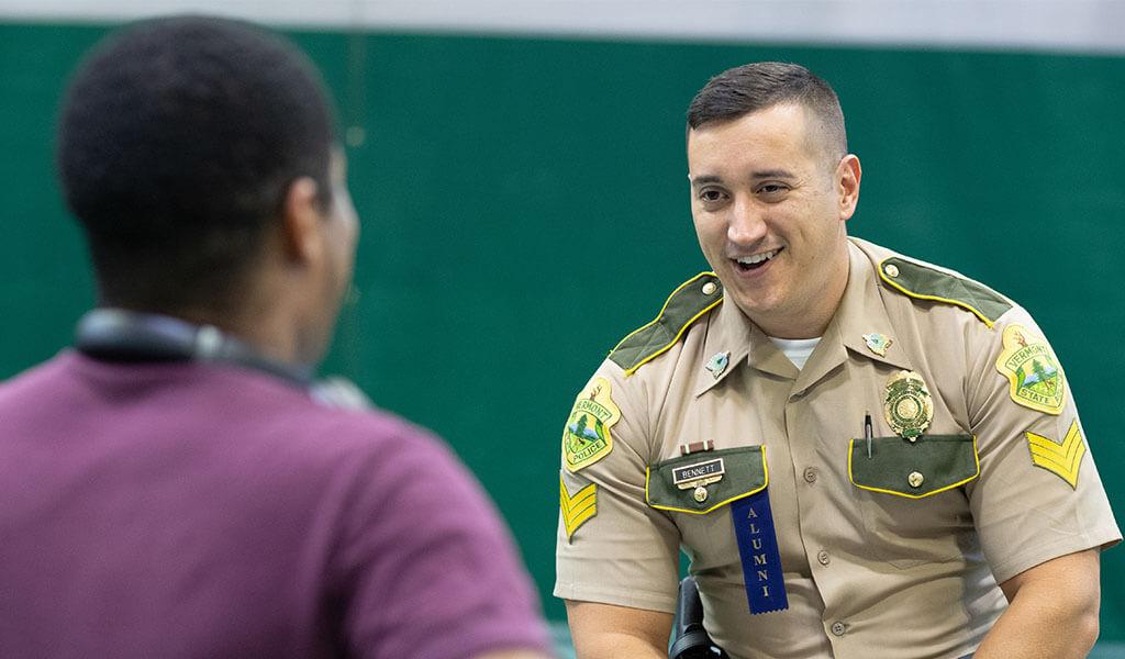 A Westfield State University alumnus in his state police uniform talks to a current student.