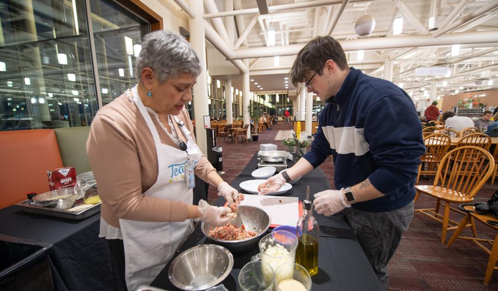 Cooking class with Maria in the Dining Commons. Photo of Maria and participant making Greek meatballs.