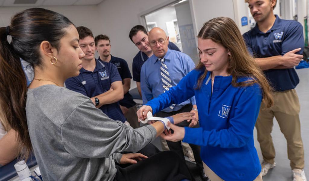 Student practicing wrist taping on a classmate in an athletic training class.