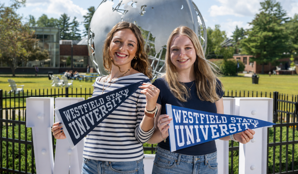 Two students on the first day of classes smiling holding WSU pennant flags.