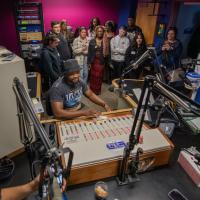 A group of students and an instructor gather around a recording studio.