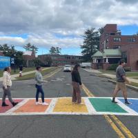 A rainbow sidewalk on campus, with four education majors mirroring the famous Beatles' album cover depicting the same.