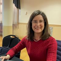 Accounting professor smiling wearing red shirt and glasses.