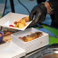 A close-up shot of Chef Ming from the Iron Chef at the University's annual fall food show. There's a stack of white, square plates, and homemade bings on them, which are Chinese streetfood crepes.