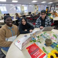 Three students in the CARE Center smiling at round table.