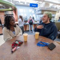 Two students converse and drink smoothies while seated at a table in one of Westfield State University’s on-campus dining facilities.