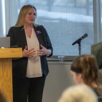 Woman stands at podium speaking to an audience