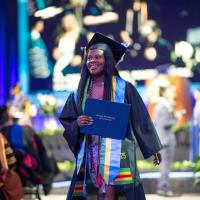 Graduate walks from stage holding diploma